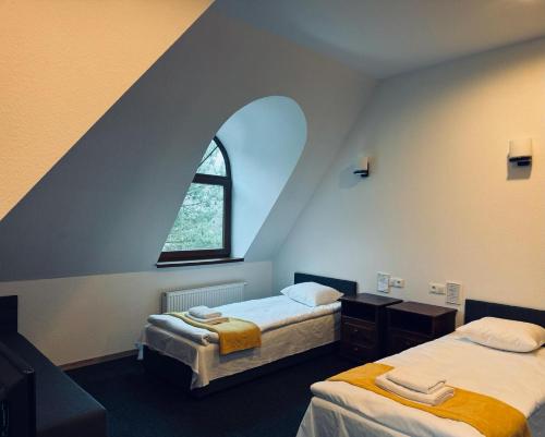 two beds in a room with an arched window at Dworek Rynarzewo 