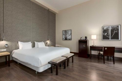 a hotel room with a large white bed and a desk at NH Den Haag in The Hague