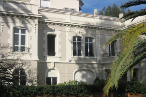een wit huis met een palmboom ervoor bij HENRI CAMILLE -POMPADOUR - Studio city center - 8 min Palais in Cannes