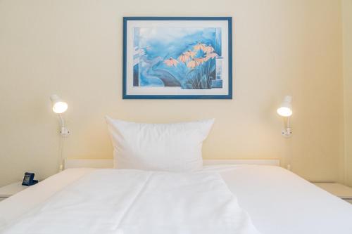 een slaapkamer met een wit bed en een schilderij aan de muur bij Haus Sola Bona Sola Bona App 34 in Westerland
