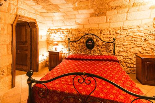 メレンドゥーニョにあるMasseria Relais Saraceno With Pool - Happy Rentalsの石壁のベッドルーム1室(赤いベッド1台付)