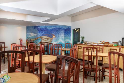 a restaurant with wooden tables and chairs and a painting on the wall at Lym Flat Hotel in Uberlândia