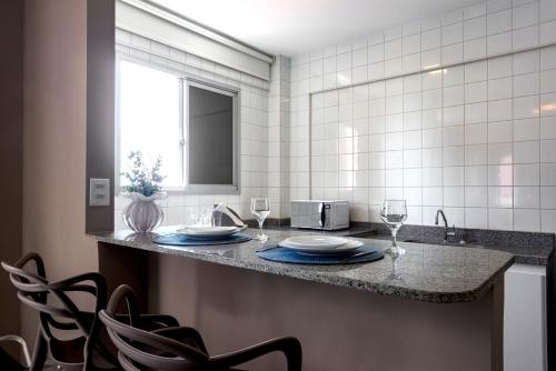 a kitchen with a counter with plates and wine glasses at Lym Flat Hotel in Uberlândia