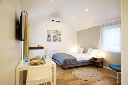 1 dormitorio con 1 cama y 1 mesa en una habitación en Folga Resort en Mrzeżyno