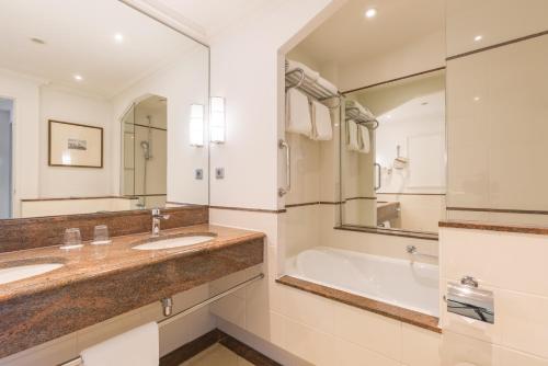 a bathroom with two sinks and a tub and a mirror at Grand Hotel Amrâth Kurhaus The Hague Scheveningen in Scheveningen