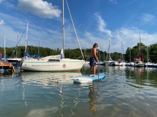 a man standing on a paddle board in the water at Przystań Caryńska w Polańczyku in Polańczyk