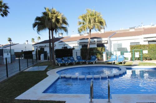 una piscina con sillas y palmeras y un edificio en K214 Apartamento Las Dunas Oliva Nova, en Oliva