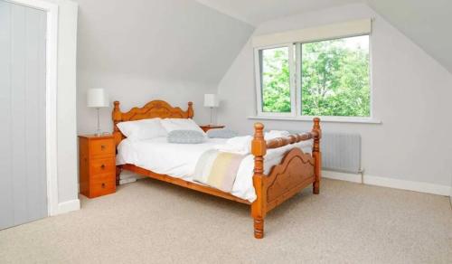 a bedroom with a wooden bed and a window at Ellie's Farmhouse in Ard Fhearta