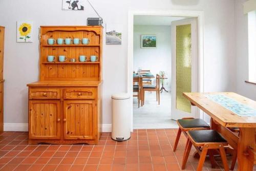 a kitchen with a wooden cabinet and a dining room at Ellie's Farmhouse in Ard Fhearta