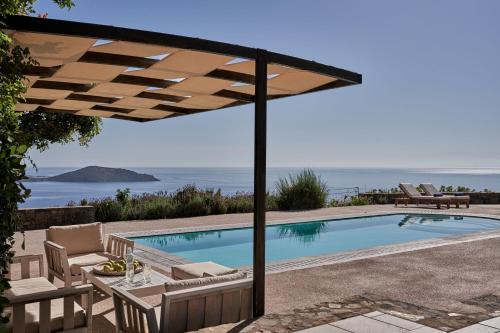 a swimming pool with an umbrella and a table and chairs at Elounda White Pearl Villa in Agios Nikolaos