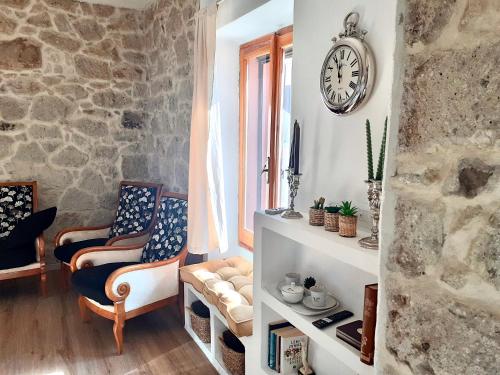 a room with two chairs and a clock on the wall at SARDEGNA DEL NORD - BELLISSIMA CASA CON TERRAZZA - INTERNET Wifi in Laerru