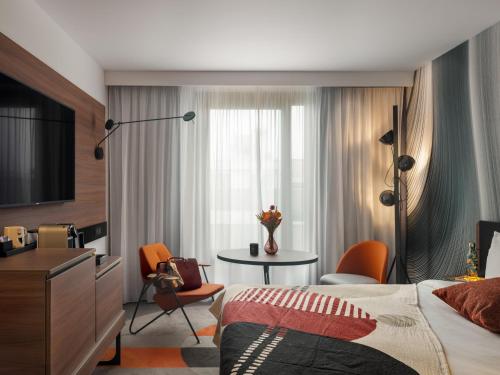 a hotel room with a bed and a table with chairs at Novotel Paris Vaugirard Montparnasse in Paris