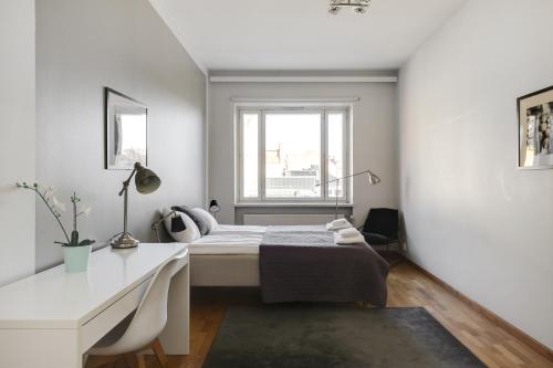 a bedroom with a bed and a desk and a window at Kotimaailma Apartments Kamppi - spacious 1BR in Helsinki