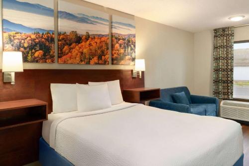a hotel room with a bed and a blue chair at Days Inn by Wyndham Dillon in Dillon