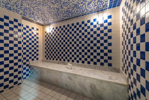 a bathroom with a tub with blue and white tiles at Best Western Plus Tabuk City Center in Tabuk