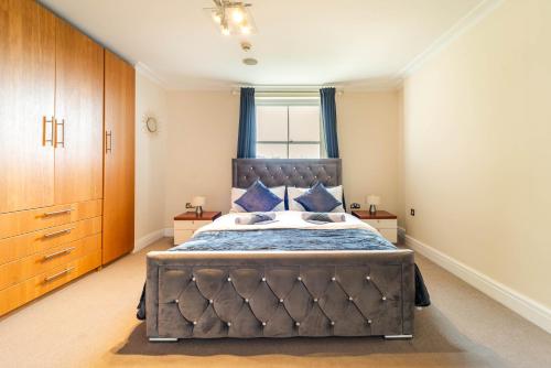 ein Schlafzimmer mit einem großen Bett mit blauen Kissen in der Unterkunft PLACIFY Riverside Penthouse in Chelsea Near King's Road in London