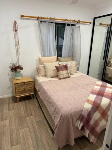 a bedroom with a bed with a pink blanket and a table at Glass Street Retreat in Kalbarri