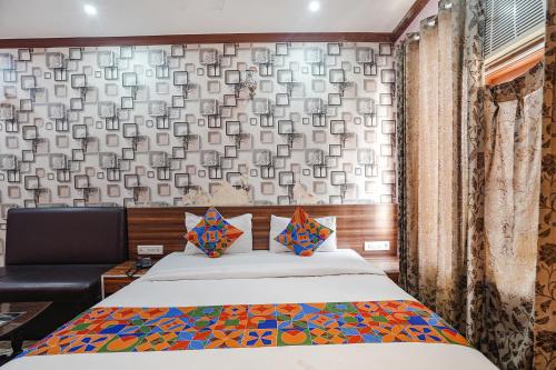 a bedroom with a bed and a wall with a window at FabHotel Deepak Palace in Varanasi