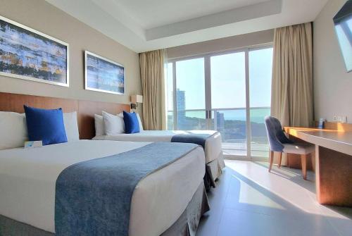 a hotel room with two beds and a desk at Wyndham Manta Sail Plaza Hotel and Convention Center in Manta