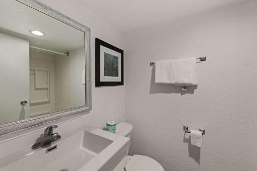 a bathroom with a sink and a toilet and a mirror at Quality Inn & Suites near I-480 and I-29 in Council Bluffs