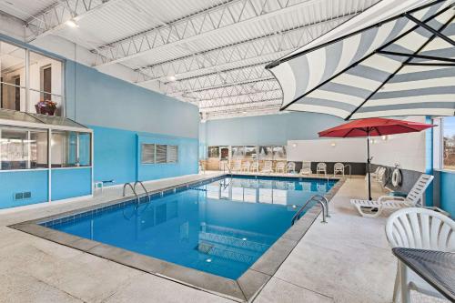 a large swimming pool with a red umbrella in a building at Quality Inn & Suites Council Bluffs - Omaha East in Council Bluffs