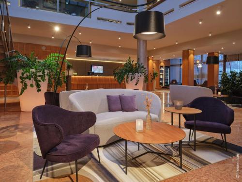 a lobby with a couch and chairs and tables at Dorint City-Hotel Salzburg in Salzburg