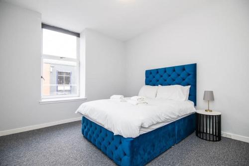 Cama azul en habitación blanca con ventana en Bright beautiful flat in Dundee en Dundee