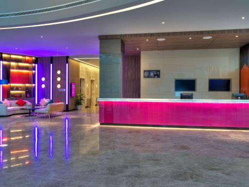 um átrio do hotel com um bar com iluminação roxa em ibis PJCC Petaling Jaya em Petaling Jaya