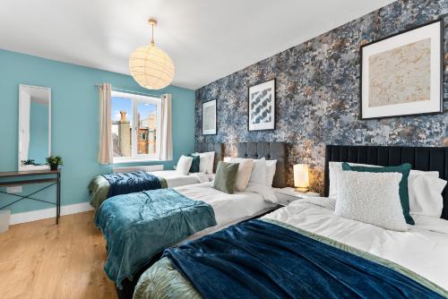 Duas camas num quarto com paredes azuis em The Chaucer - Stylish City Centre Gem - Sleeps 7 em Kent