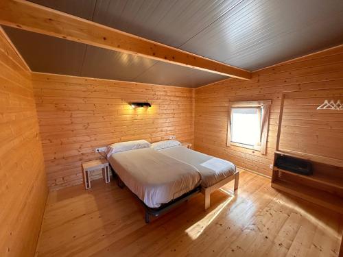 een slaapkamer met een bed in een houten kamer bij Camping & Bungalows Leagi in Mendexa