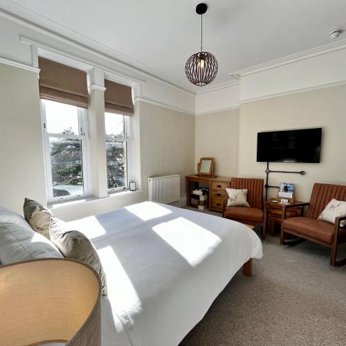 a bedroom with a large white bed and a flat screen tv at The Devonian in Ilfracombe