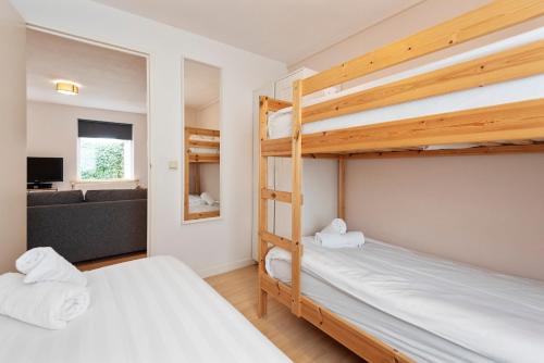 two bunk beds in a room with a couch at Spacious Family Holiday Home (7p), Free indoor parking in Zandvoort
