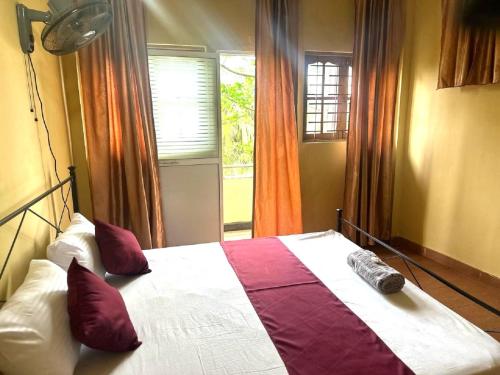 a bedroom with a bed with purple pillows and a window at Pearl River Kandy in Kandy