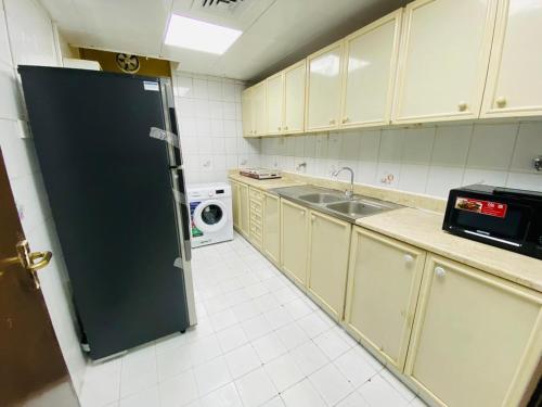 La cuisine est équipée d'un réfrigérateur noir et d'un four micro-ondes. dans l'établissement PRIVATE FAMILY ROOM BY BJ, à Abu Dhabi