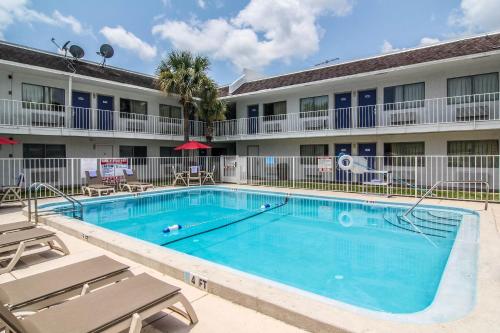 a swimming pool in front of a hotel with chairs at Motel 6-Jacksonville, FL - Orange Park in Jacksonville