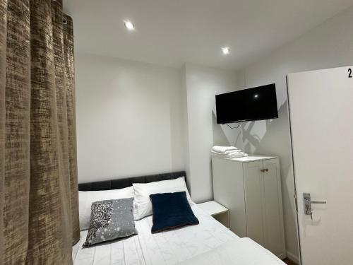 una camera da letto con un letto con due cuscini e una TV di Smart Cosy/Small Double Room in Oakridge Road Bromley a Lewisham