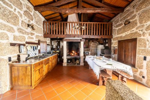 a large kitchen with a fireplace in a stone building at Casa do Souto Vieira do Minho - Casa Rural com piscina by House and People in Vieira do Minho