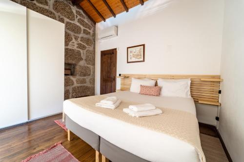 a bedroom with a large bed with towels on it at Casa do Souto Vieira do Minho - Casa Rural com piscina by House and People in Lugar