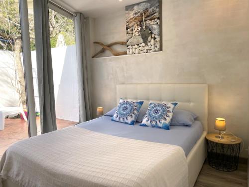 ein Schlafzimmer mit einem Bett mit blauen Kissen und einem Fenster in der Unterkunft TUSQUETS - Apartamento con vistas al mar in Cadaqués