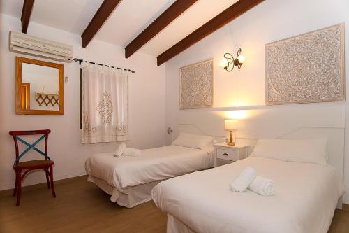 two beds in a room with white walls and wood floors at Villa Tramuntana 171 by Mallorca Charme in Inca