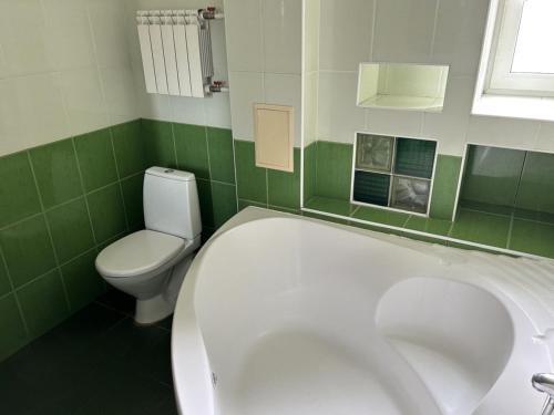 ein grün-weißes Bad mit einer Badewanne und einem WC in der Unterkunft Апартаменти 3-кімнатні, м. Майдан Незалежності in Kiew
