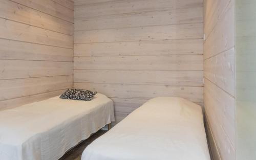 two beds in a room with wooden walls at Villa Lusma in Inari