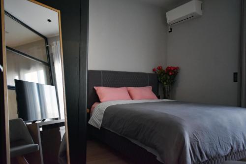 - une chambre avec un lit doté d'oreillers roses et une télévision dans l'établissement Zeus and Hera Studio, à Athènes