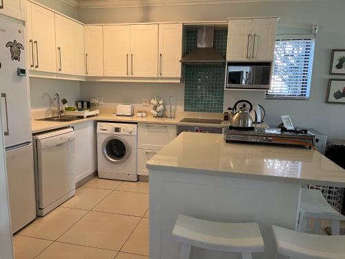 a kitchen with white cabinets and a sink and a dishwasher at Keurbooms River Lodge 21 in Keurboomstrand