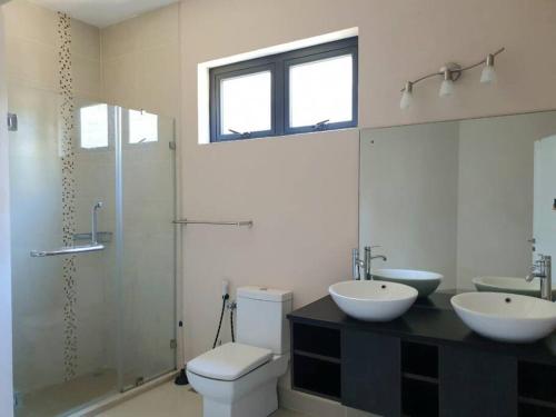 ein Badezimmer mit zwei Waschbecken, einem WC und einer Dusche in der Unterkunft Heaven Heights - Fully Furnished Air Con Apartment in Beau Bassin-Rose Hill