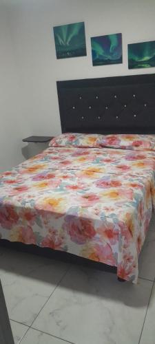 a bed with a floral comforter in a bedroom at Apartamento de 2 habitaciones en Robledo a 20 minutos del centro in Medellín