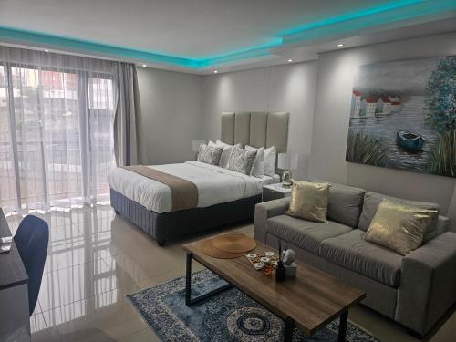 a bedroom with a bed and a couch and a table at Glorystar The Millennial Umhlanga in Durban