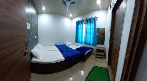um pequeno quarto com uma cama com uma cortina azul em Hotel Shiv Ganga em Varanasi