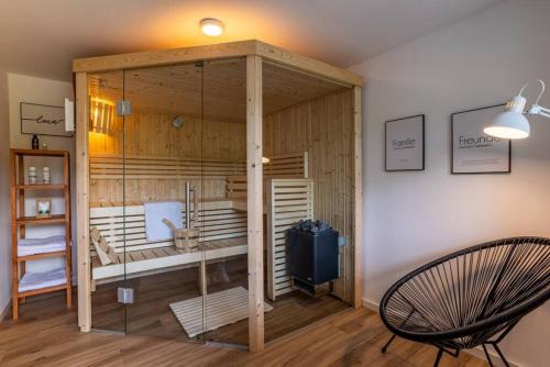 KerpenにあるAdenauer Zwölf - Das 5 Sterne Ferienhaus mit Sauna und Garten am Eifelsteigのサウナと椅子が備わる客室です。