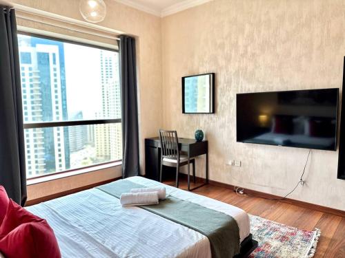 a bedroom with a bed and a desk and a large window at Sunkissed holiday homes Stunning marina view 4BR plus maid room on JBR beach near mall in Dubai